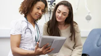 A nurse shows a young woman her test results from a preventive screening.