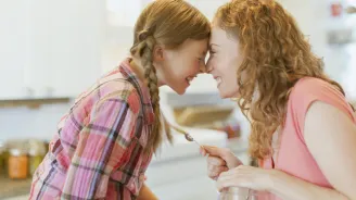 Mother and teen daughter laughing in the kitchen