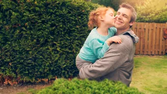 daughter hugging and kissing father outside