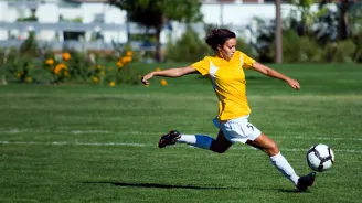 A female soccer playing kicking a soccer ball