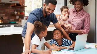 Photo of a family standing at a laptop making plans and smiling.