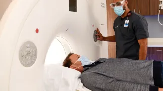 Man getting a CT scan while him and imaging tech wear masks.