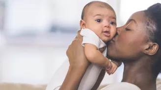 Mother holding and kissing her baby.
