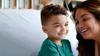 Mother with her son who is sitting on a hospital bed.