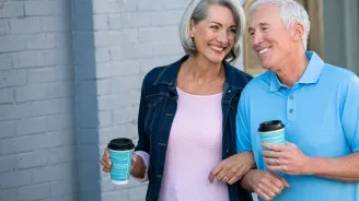 Older couple walking with coffee