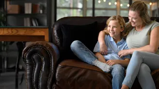 A Mother and Her Child Sit on a Couch at Home