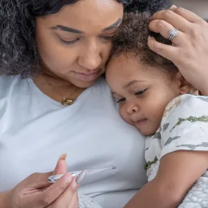 Mom taking temperature of little girl