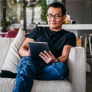 A man reading on his tablet at home.