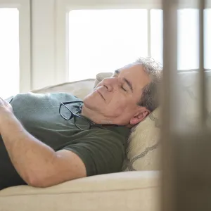 An adult Caucasian man takes an afternoon nap on the couch.