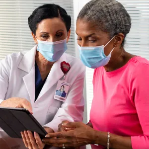 A doctor showing a patient something on her business tablet