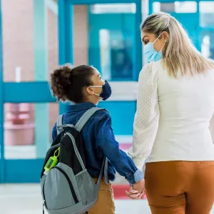Mother and daughter walking hand in hand through the hallways of a school