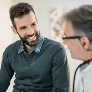 A dark haired and bearded adult man with a male Doctor.