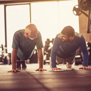 Two men do push-ups in a gym.