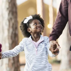 Young girl walks with her parents at the park