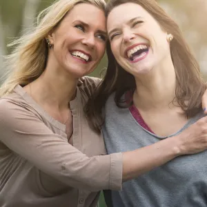 Two sisters hugging and laughing.