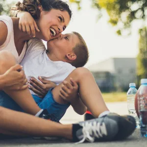 A mother and son take a water break on the basketball court during the summer.