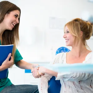 A woman in a lab, shaking hands with a lab tech after getting blood drawn.