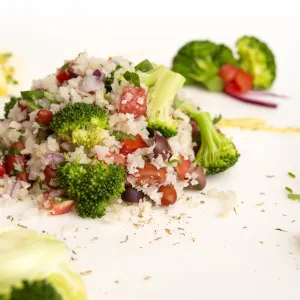 Mound of cauliflower rice salad with lemon and broccoli garnishes