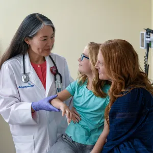 A Centra Care Physician Checks a Little Girl's Arm With Her Mom Watching