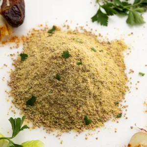 Mound of chicken-style seasoning on white surface surrounded by garnishes