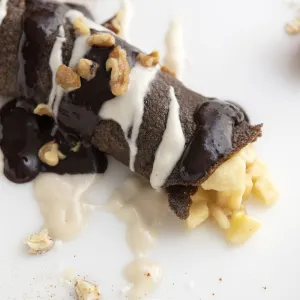 Chocolate crepe with banana filling on white surface