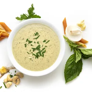 Bowl of vegan alfredo with herb and nut garnishes