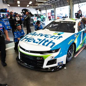 Pit crew working on the AdventHealth NASCAR car in a garage.