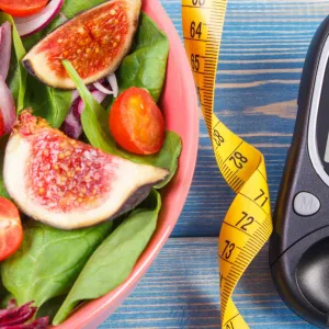A picture of a salad, measuring tape, and a sugar monitor