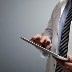 A doctor takes notes on a tablet.
