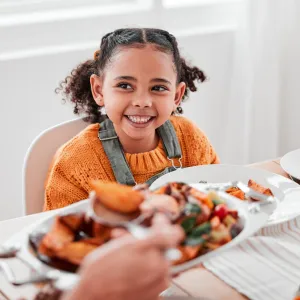 A girl smiling at the dinner table.