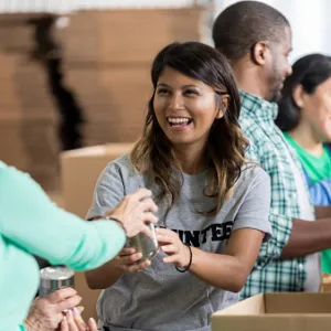 women giving woman glass while packing