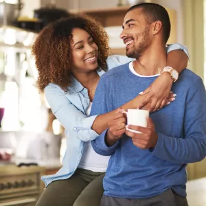 A couple hugs in their kitchen at home.