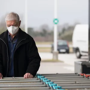 An elderly man getting a grocery cart. 