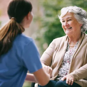 An elderly woman talks and laughs with her caretaker