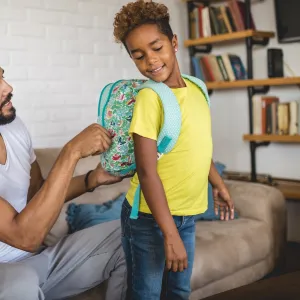 A father adjusts his child's backpack.