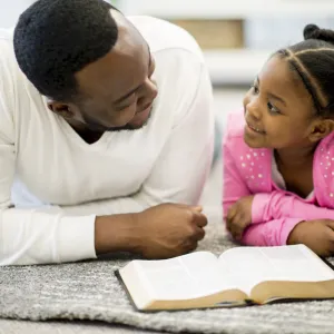 A father and daughter read the Bible together.