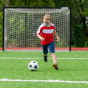 A child playing soccer with his mask on