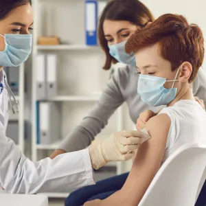 A teenager getting a vaccine shot by a doctor