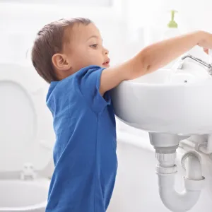 A child turning on the bathroom sink.