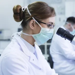 A woman looking through a microscope in a lab.