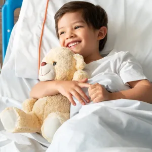 A little boy hugs his teddy bear while in the hospital.