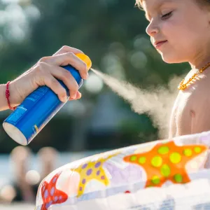 Little boy gets sunscreen protection from his mom at the beach