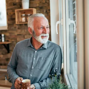 A man enjoying a cup of tea looking out the window.