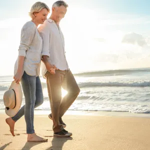 A couple walks on the beach near sunset.