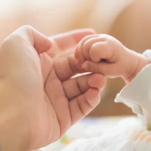 A baby holding one of her mother's fingers