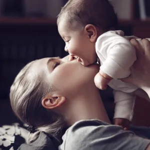 A mom kissing her giggling baby.