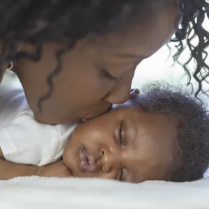 A mother kisses her newborn infant.