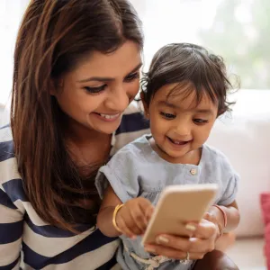 A mom uses her phone with her child.