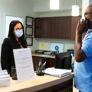 A patient checking in for an appointment and wearing a mask.