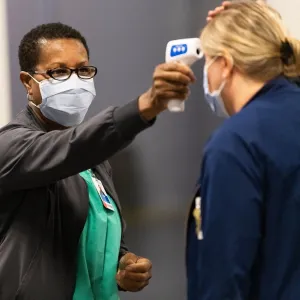 A health care worker temperature testing a patient. 